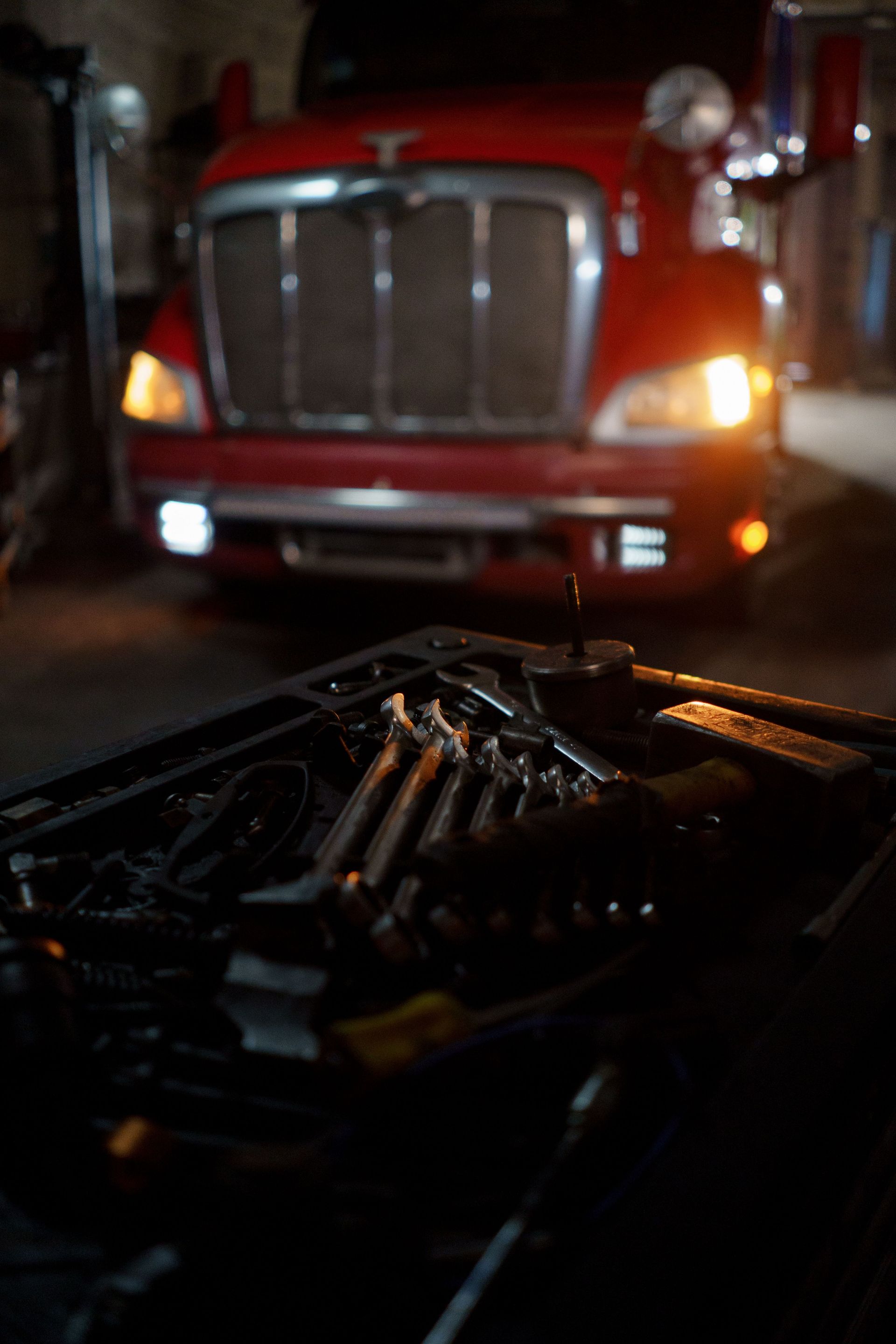 Dimly lit garage scene featuring tools and a red truck, suggesting automotive repair.